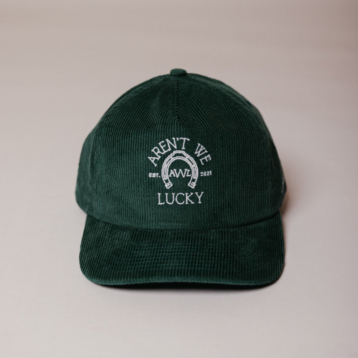A green baseball cap with text embroidery, placed on a neutral background.