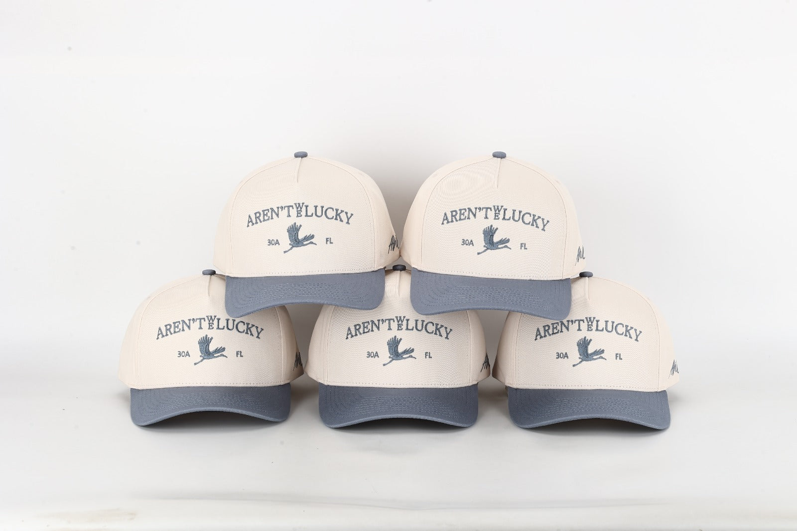 Five caps with 'Aren't We Lucky?' text on a white background