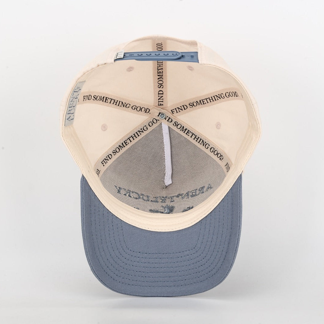 Baseball cap with beige visor and blue bill on a white background interior