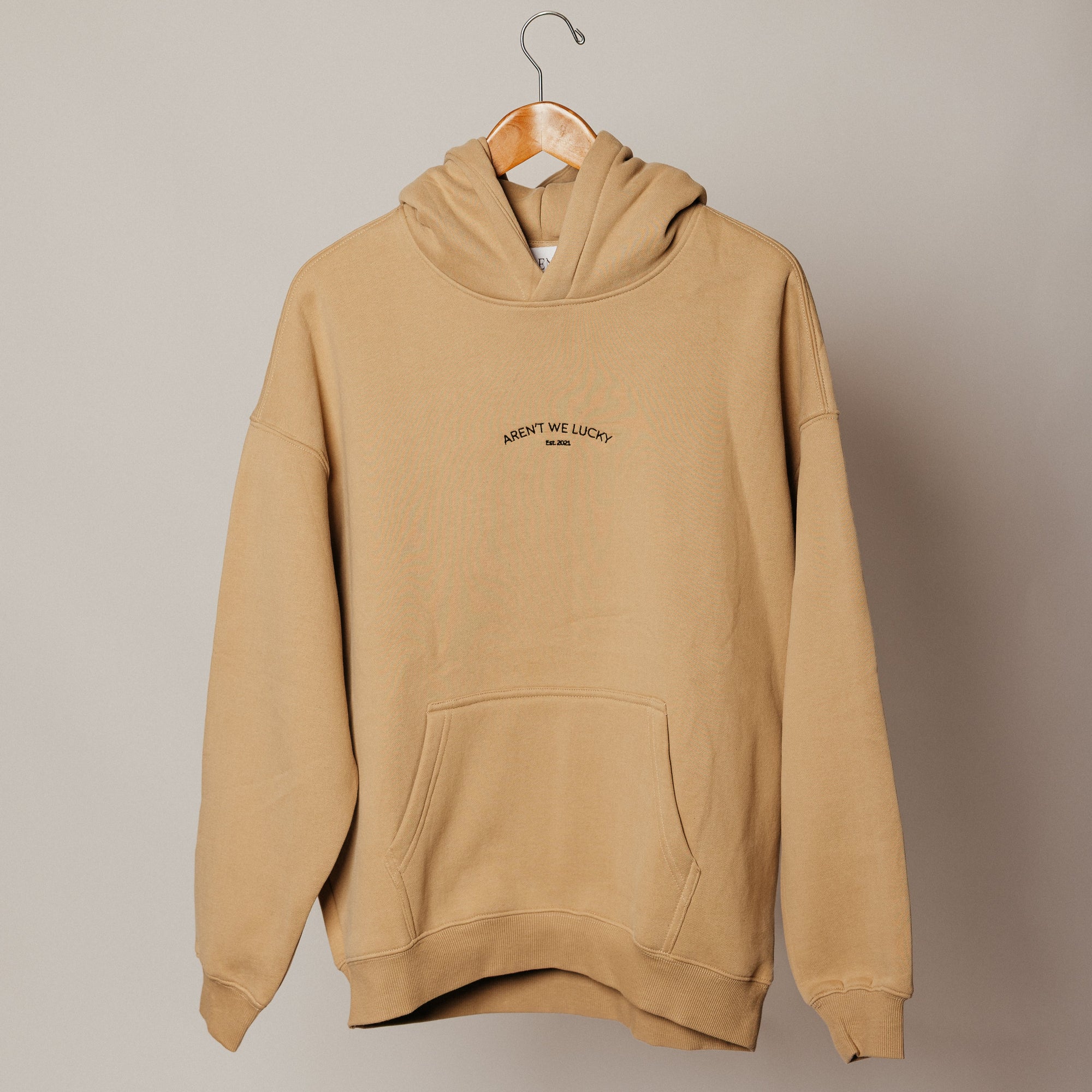 Beige hoodie on a hanger against a plain background