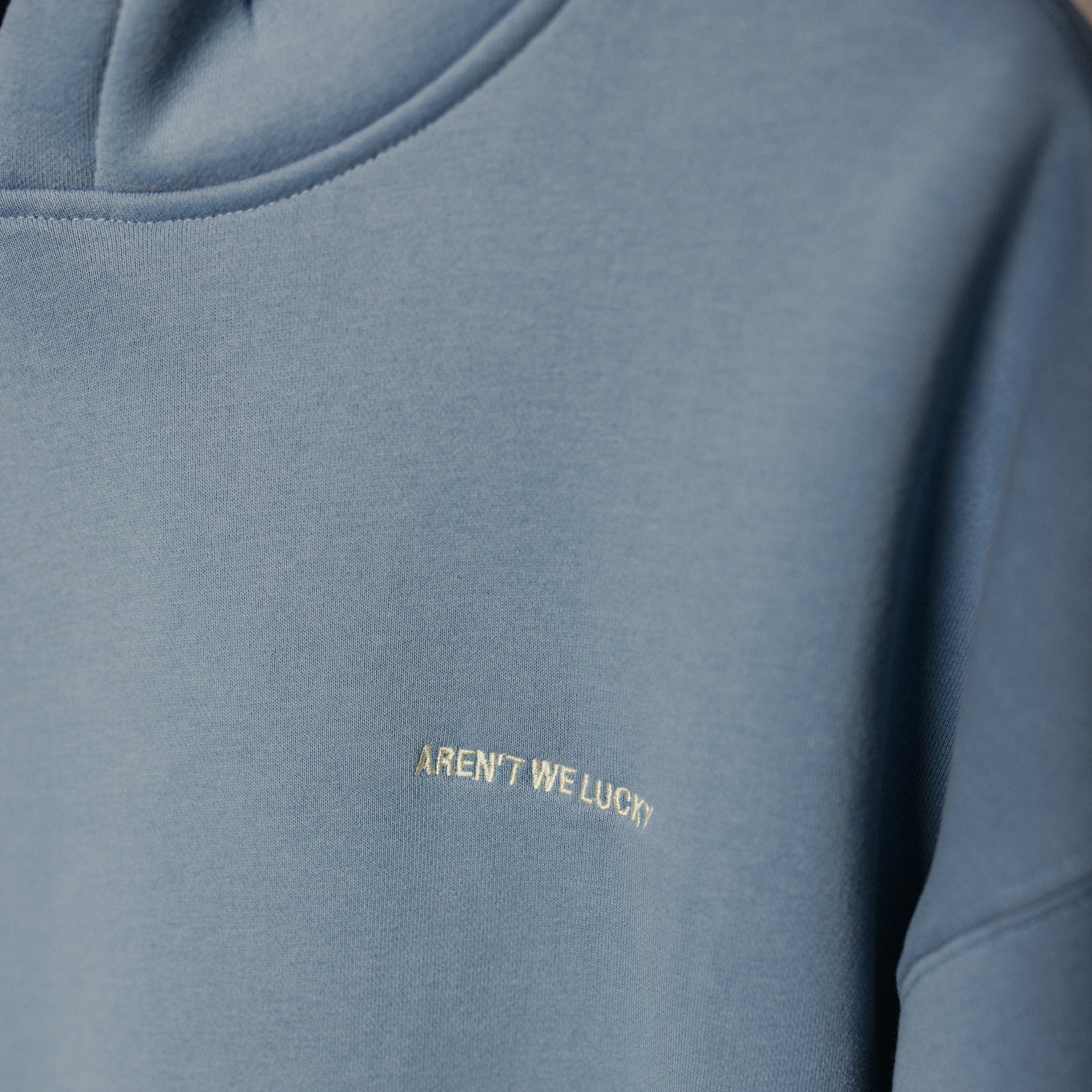 Blue hoodie with 'Aren't We Lucky' text on a dark background