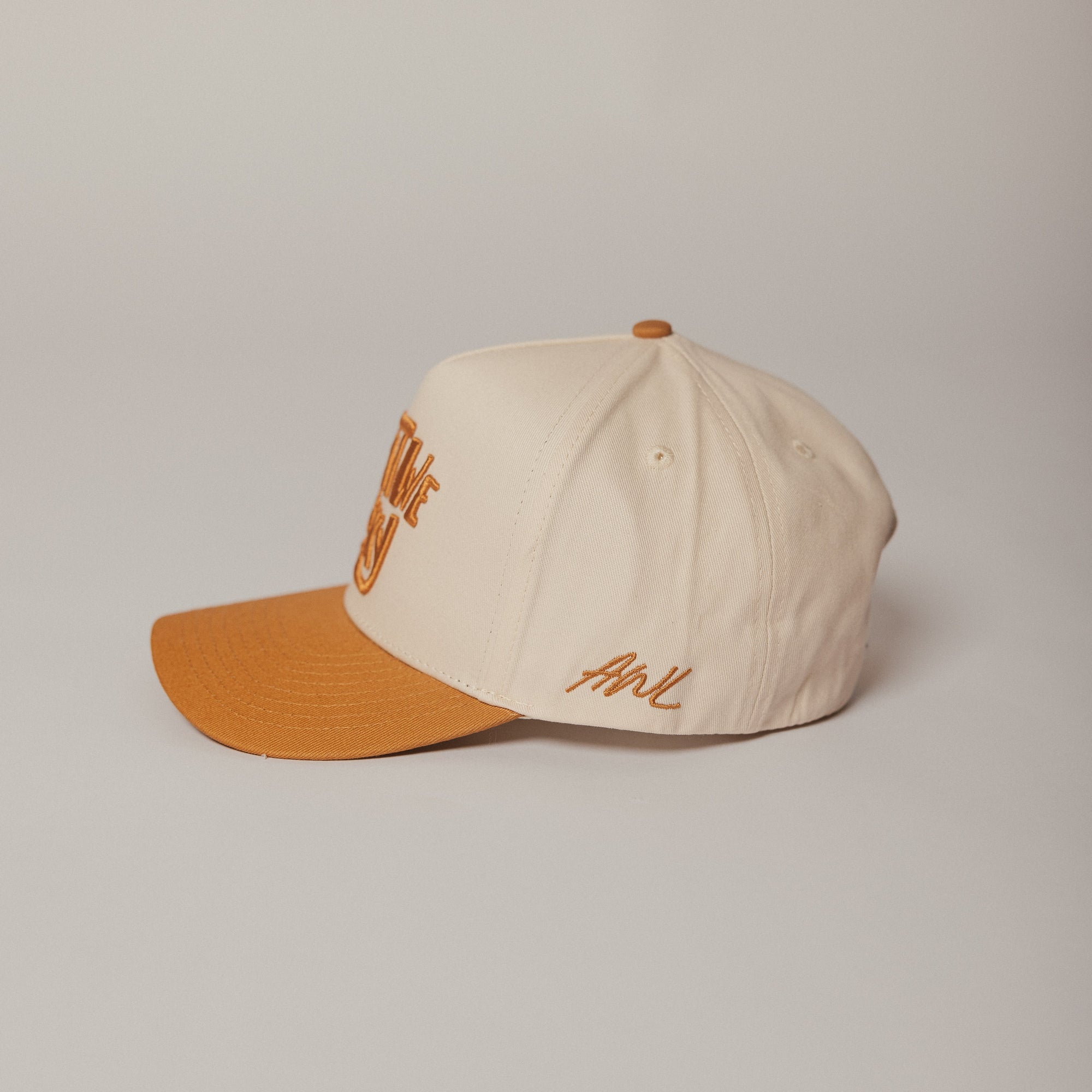 Two-tone cap with beige top and orange brim on a light gray background